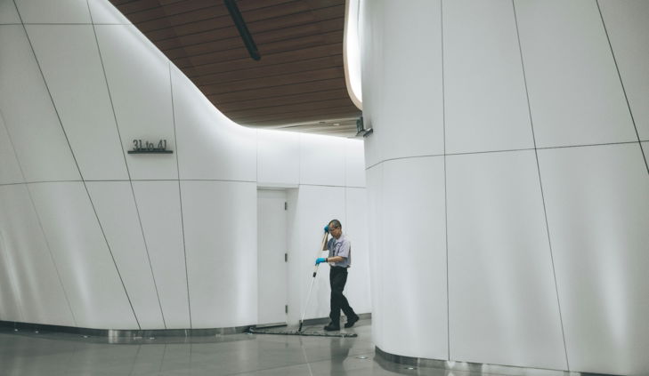 man cleaning on floor beside white wall